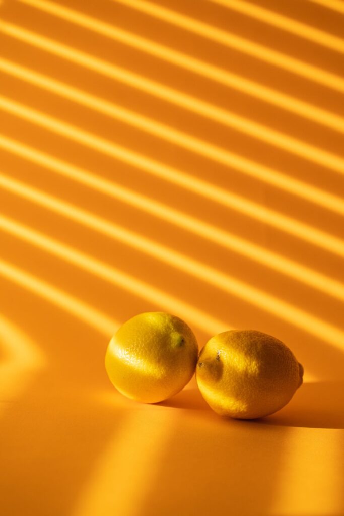 Zitronen liegen auf Tisch mit orangem Hintergrund und Schatten 