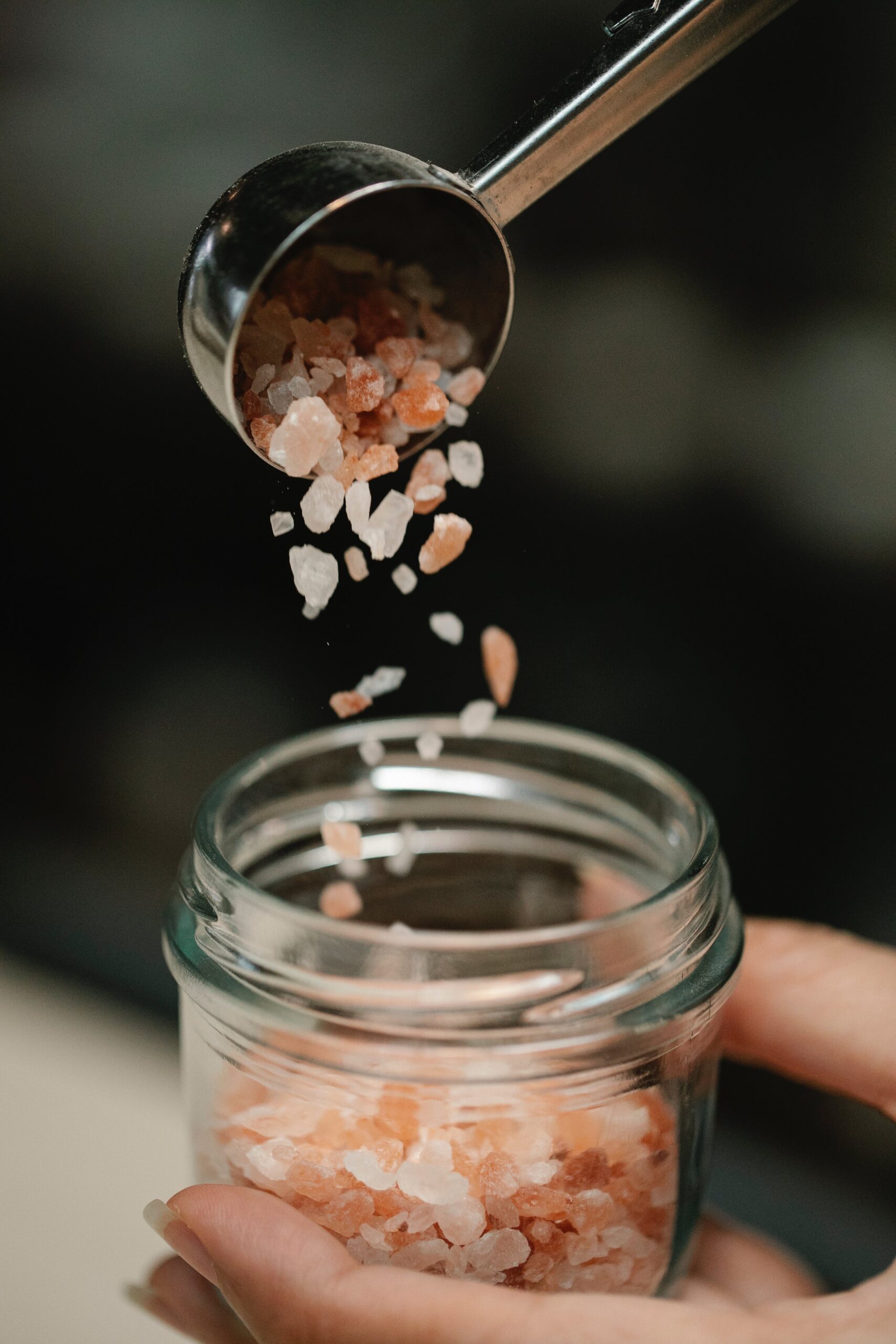 Salzkörner werden in ein Glas geschüttet.