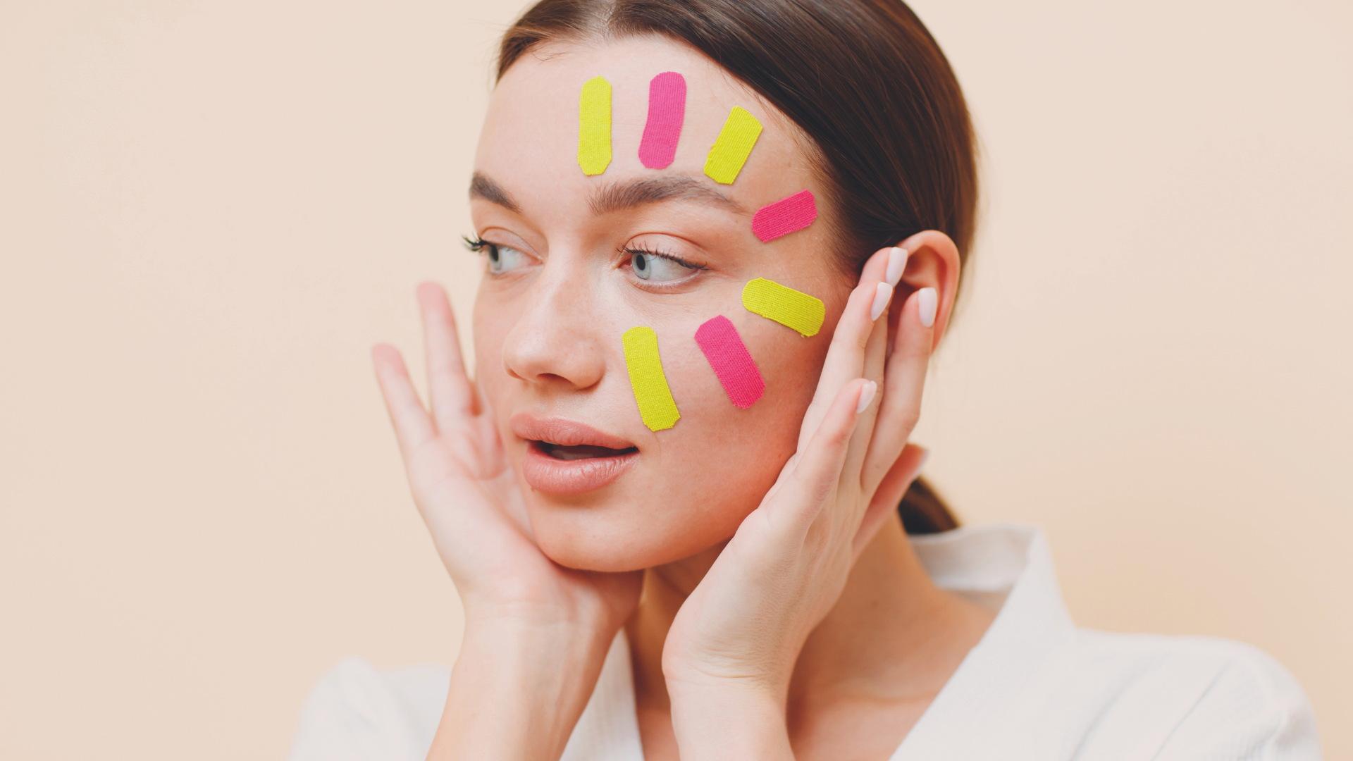 bunte facetapes auf dem Gesicht einer brünetten jungen Frau