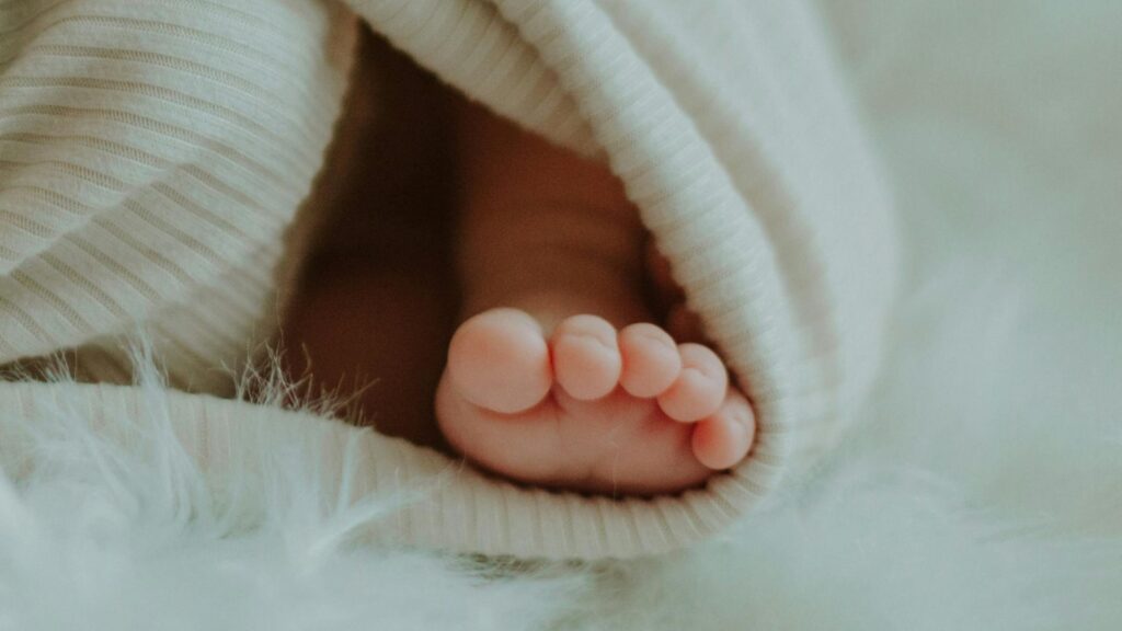 Fuß eines Babys, eingewickelt in eine weiße Decke.