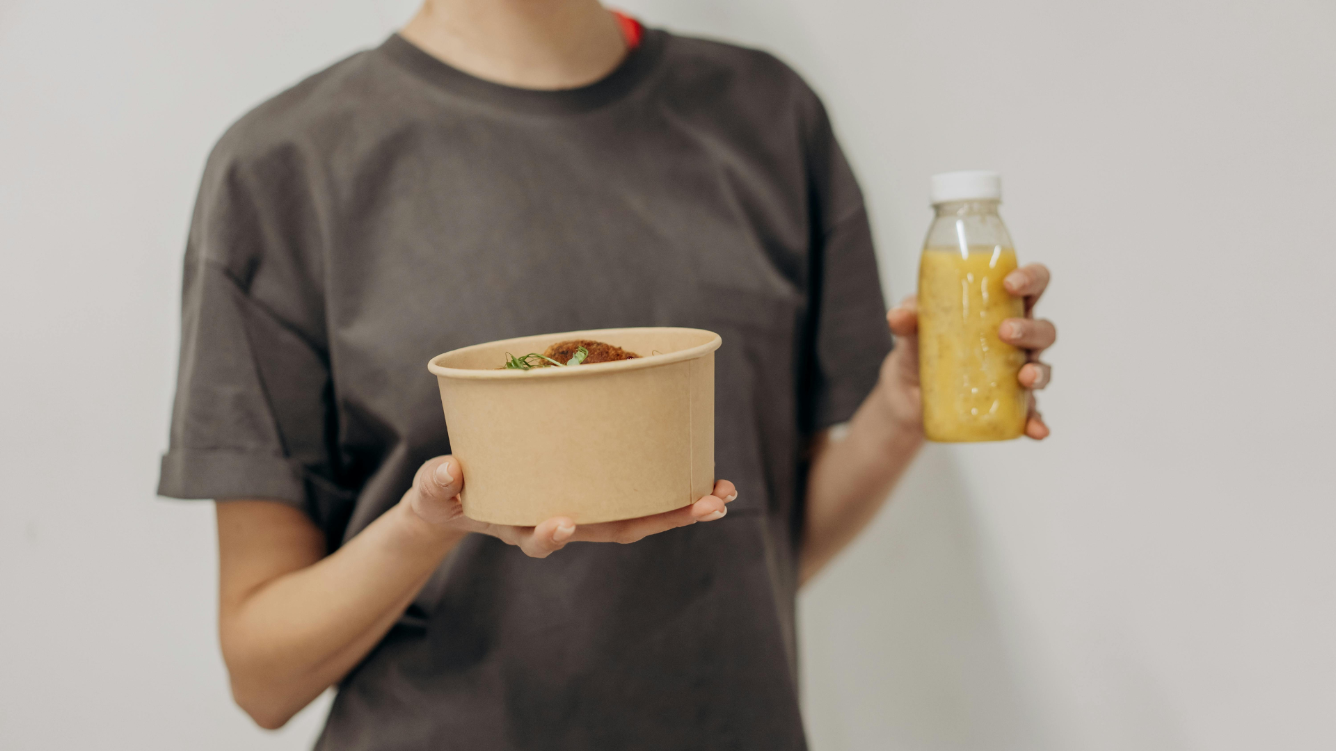 Lecker und gesund: Frau hält gesunde Bowl und Drink in der Hand