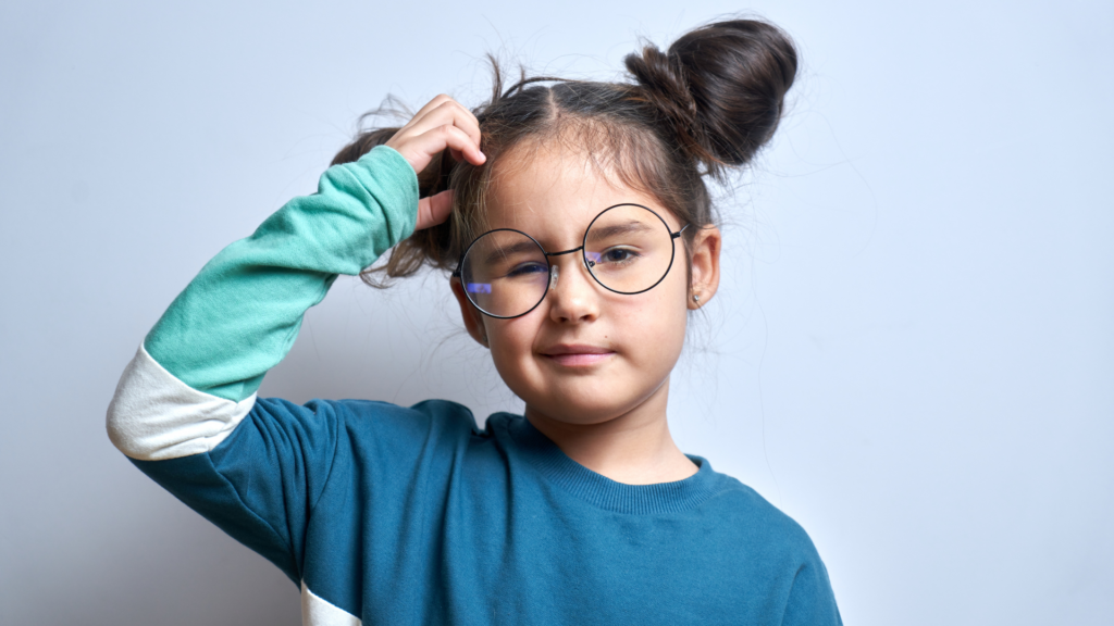Kleines Mädchen mit Brille kratzt sich ratlos am Kopf.
