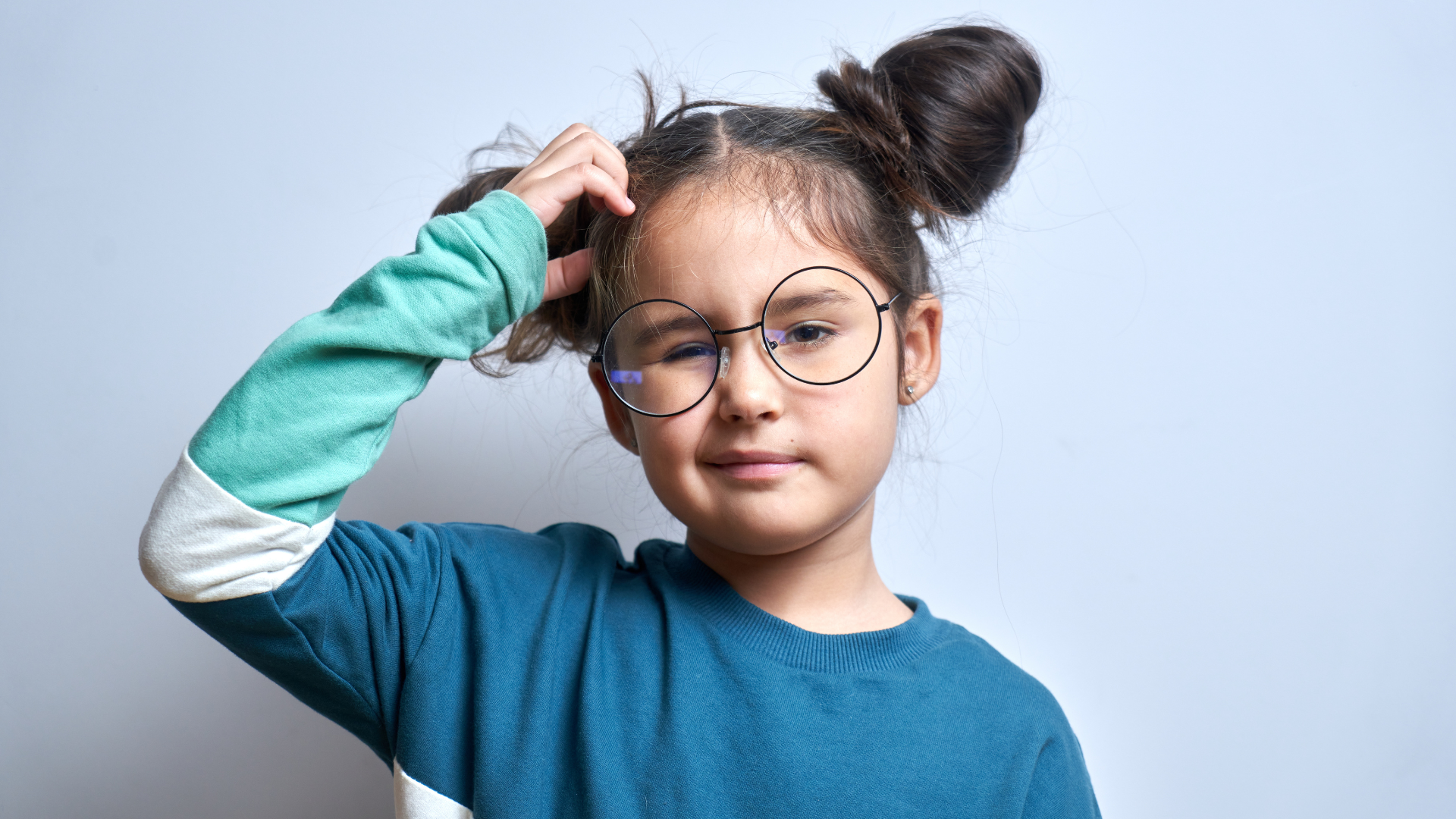 Kleines Mädchen mit Brille kratzt sich ratlos am Kopf.
