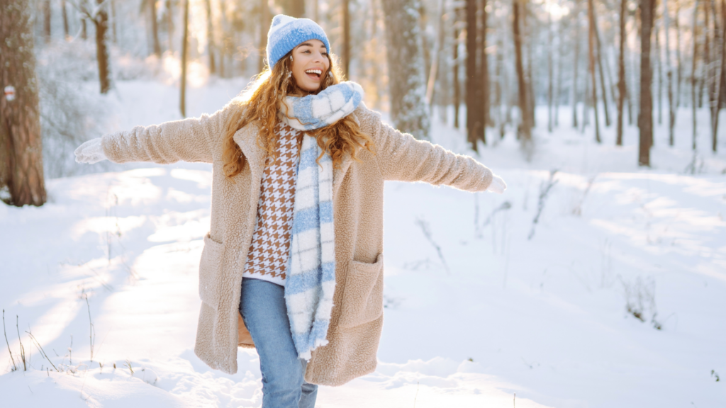 Junge Frau geht gutgelaunt im Schnee spazieren