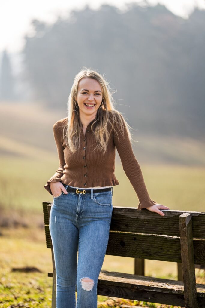 Biobäuerin Vanessa Aufreiter lehnt an einer Holzbank im Garten