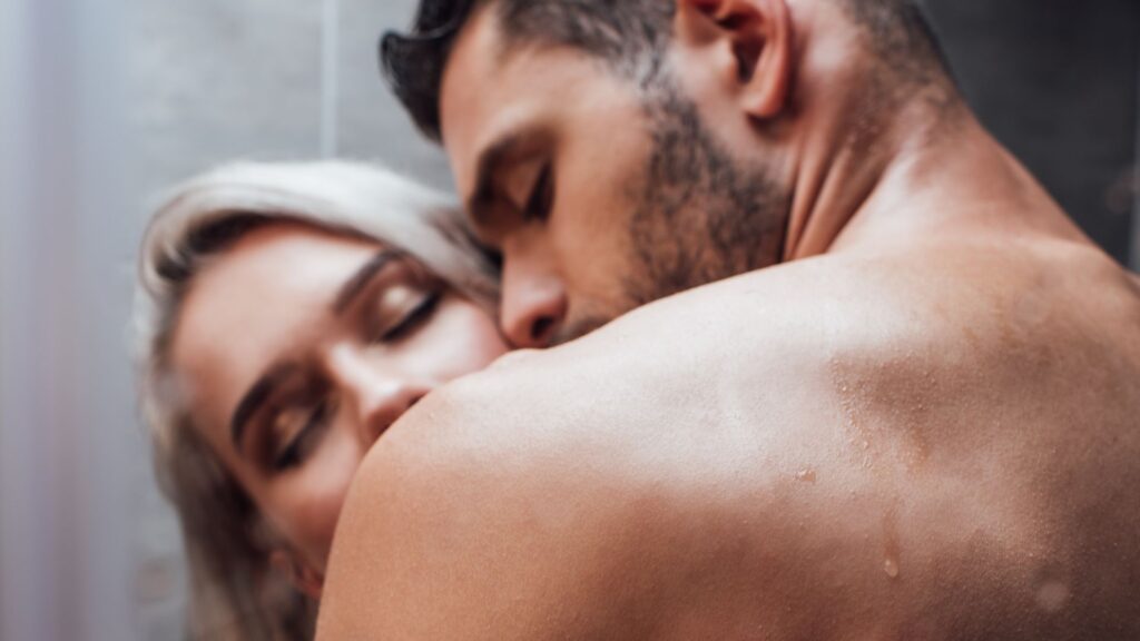 Frau und Mann küssen sich unter der Dusche