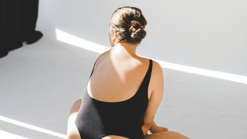 Eine Frau sitzt im Body auf dem Boden