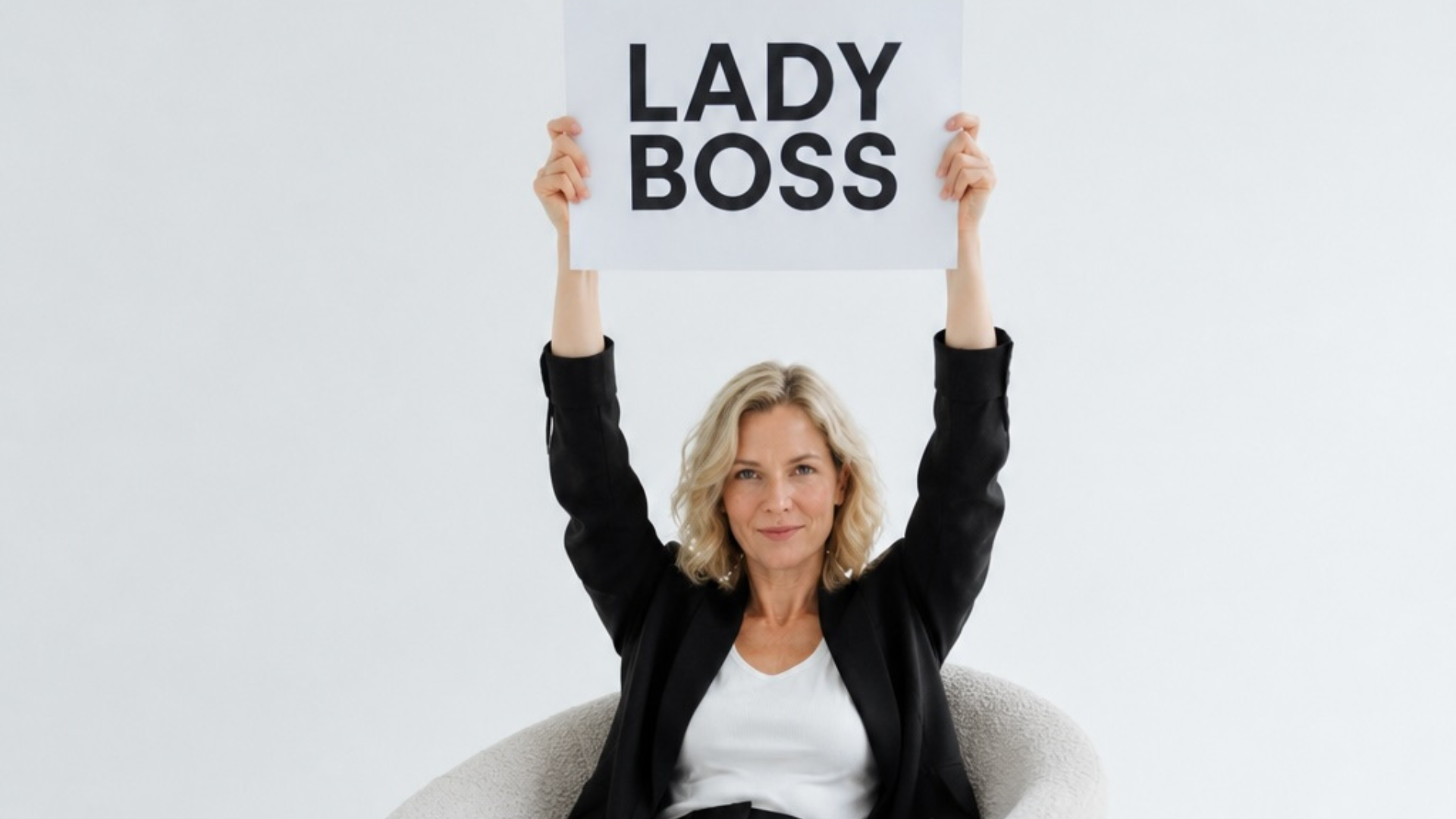 Frau sitzt in Sessel und hält Schild mit Aufschrift "Lady Boss" hoch