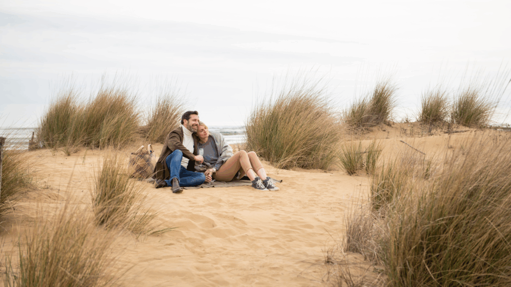 Ein Mann und eine Frau kuschelnd und lachend in den Dünen