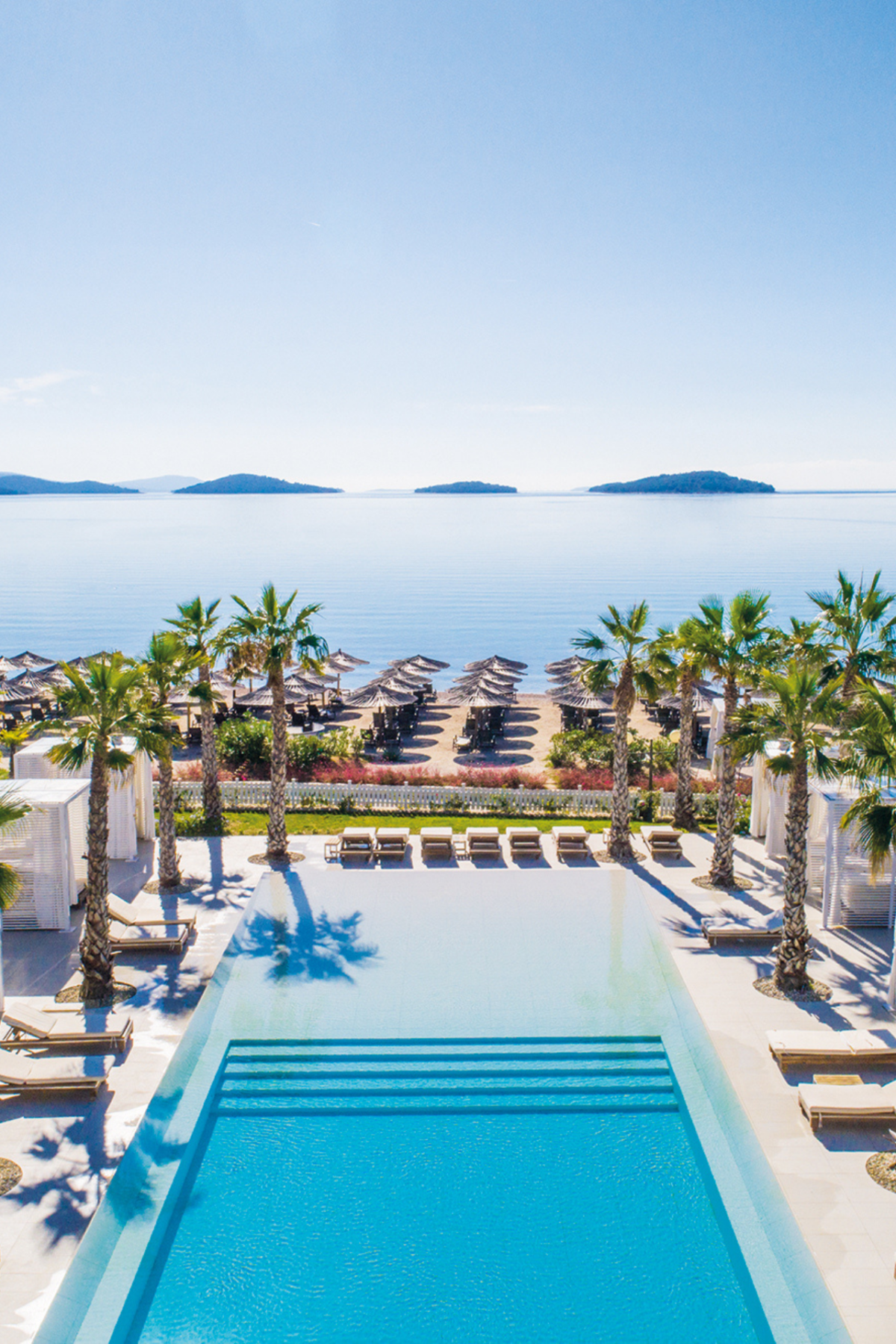 Gewinne ein Wochenende im Amadria Park Hotel Jure. Das Bild zeigt die Hotel-Poollandschaft umringt von Palmen mit Blick aufs Meer.
